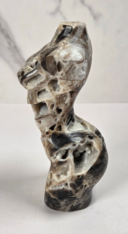 Druzy quartz carved female torso against a white background
