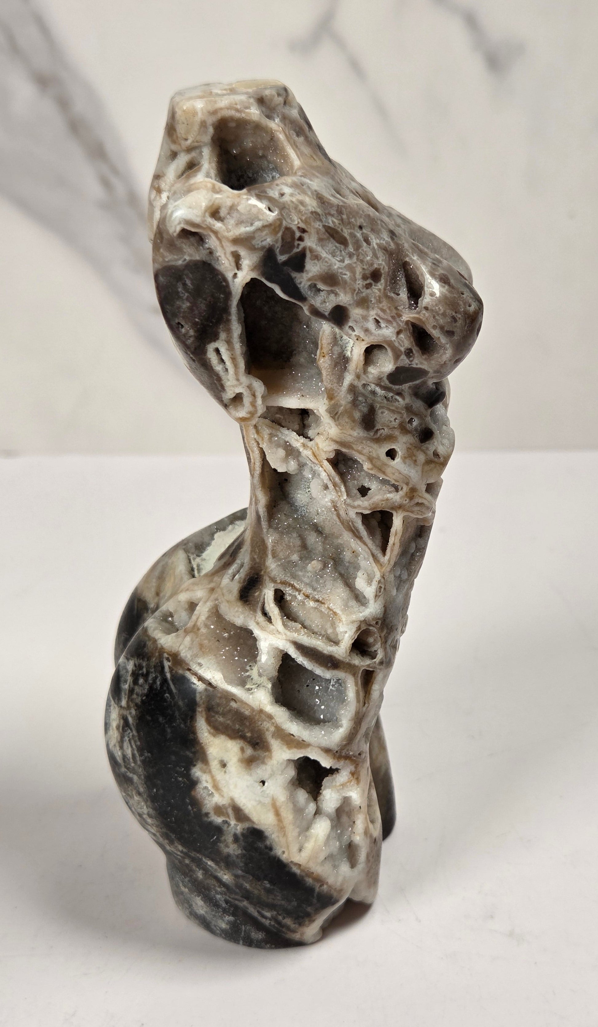 Druzy quartz carved female torso against a white background