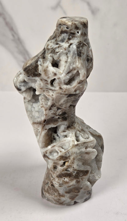 Druzy quartz carved female torso against a white background