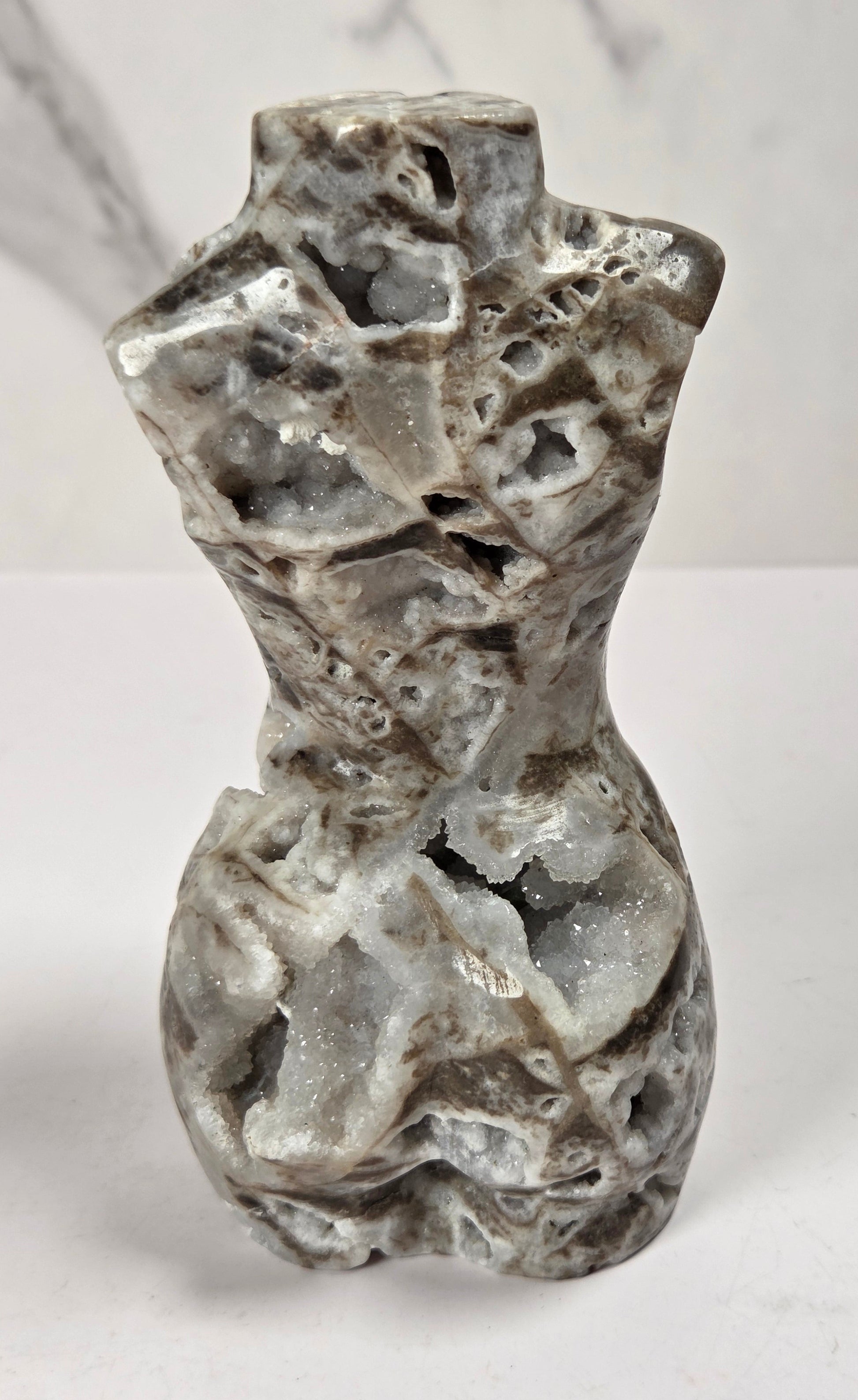 Druzy quartz carved female torso against a white background