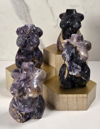 Four polished stone figurines shaped like bears, displayed on geometric gold-colored pedestals against a white marble-patterned background.