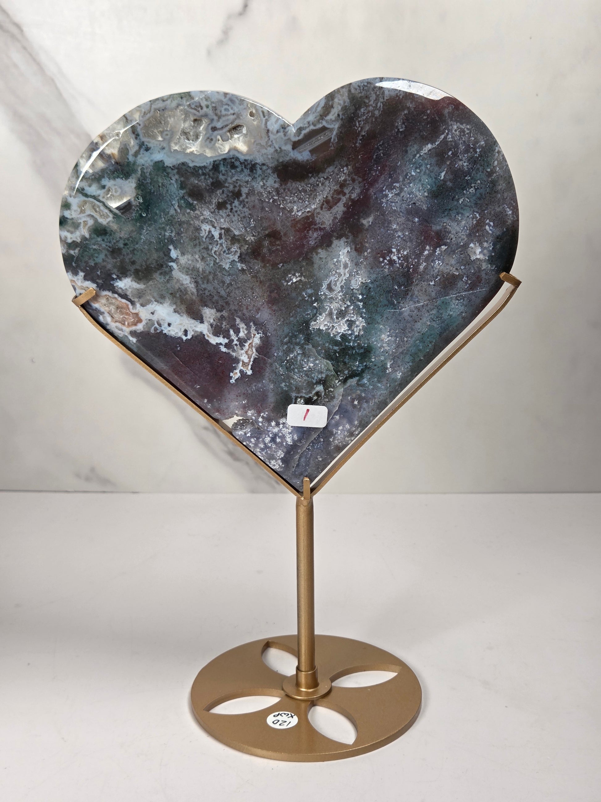 Heart-shaped agate stone plaque on a gold metal stand, displayed against a light gray marble-patterned background.