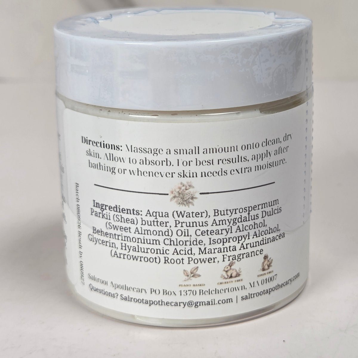 A clear plastic jar of Salvia Apothecary body butter with a white lid and white label, photographed on a light neutral background.
