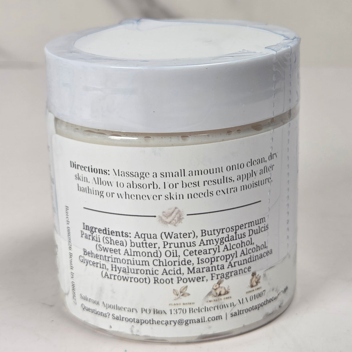 A white jar of facial cleansing foam with a white lid, showing the back of the label with product details, set against a neutral light gray background.