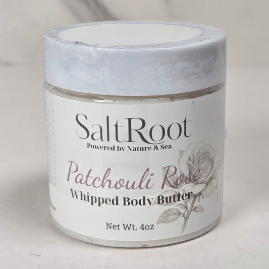 A jar of SaltRoot Patchouli Rose Whipped Body Butter on a light marble-like surface with a soft gray background.