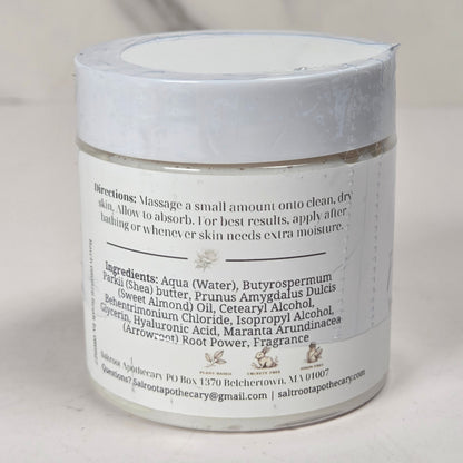 A white cosmetic jar with a white lid and a white label showing the back side with product ingredients and directions, set against a light marble background.