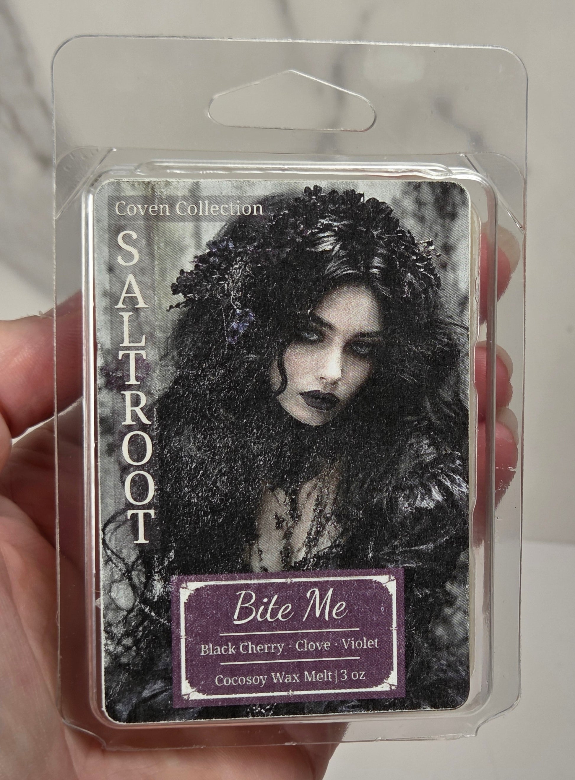Hand holding a package of wax melts that are called Bite Me against a white background