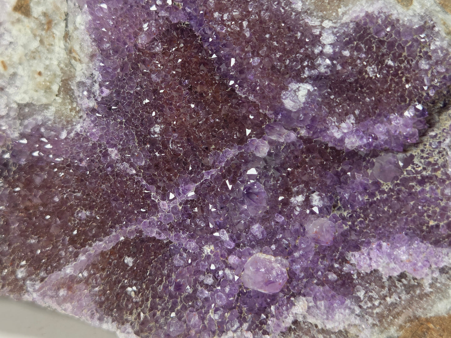 Close-up of a purple mineral specimen or crystal cluster with a textured, crystalline surface and some lighter translucent areas.