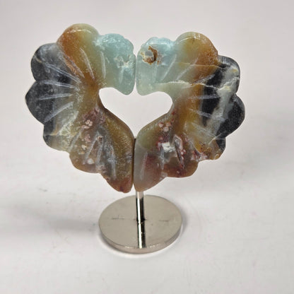 A carved stone heart-shaped earring with two lotus-like petals, displayed on a small metal stand against a light gray background.