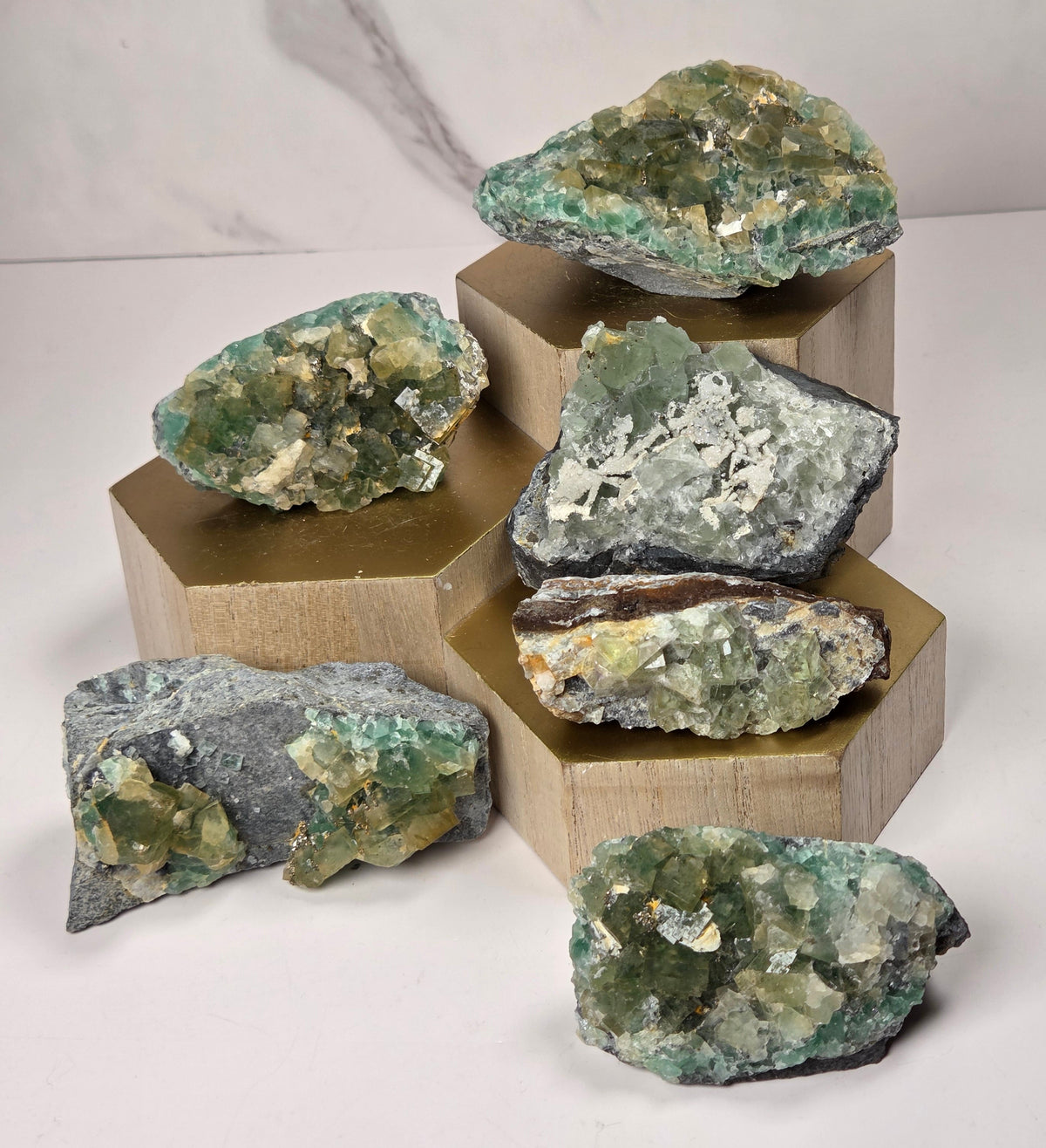 Green and yellow colored fluorite specimens on a wood display against a white background