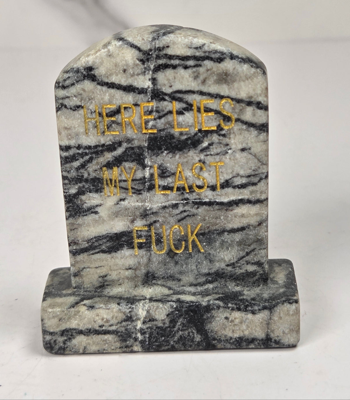 Spiderweb Jasper tombstone carving with gold lettering against a white background