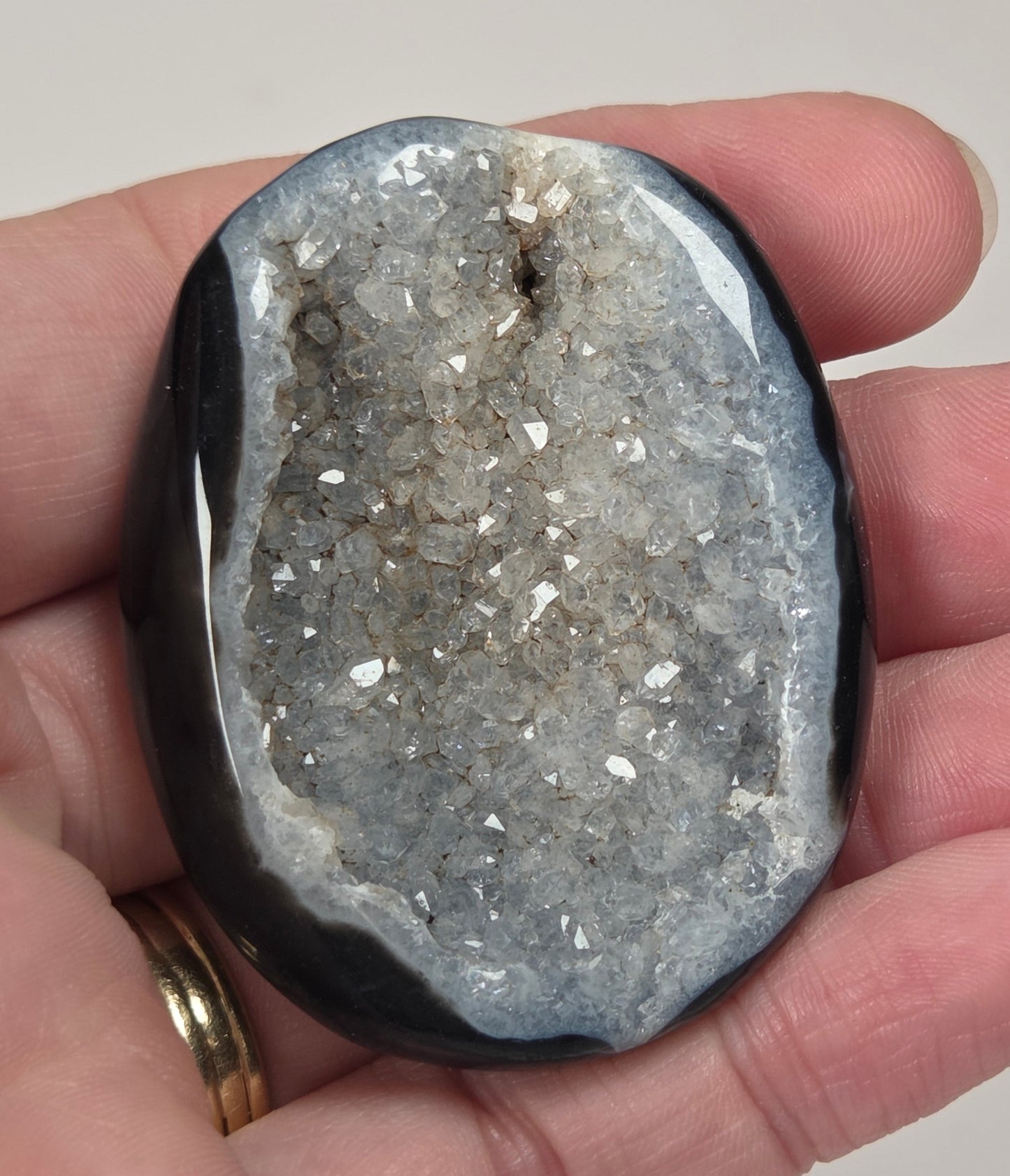 Black agate palm carving with white quartz crystals being held in a hand against a white background