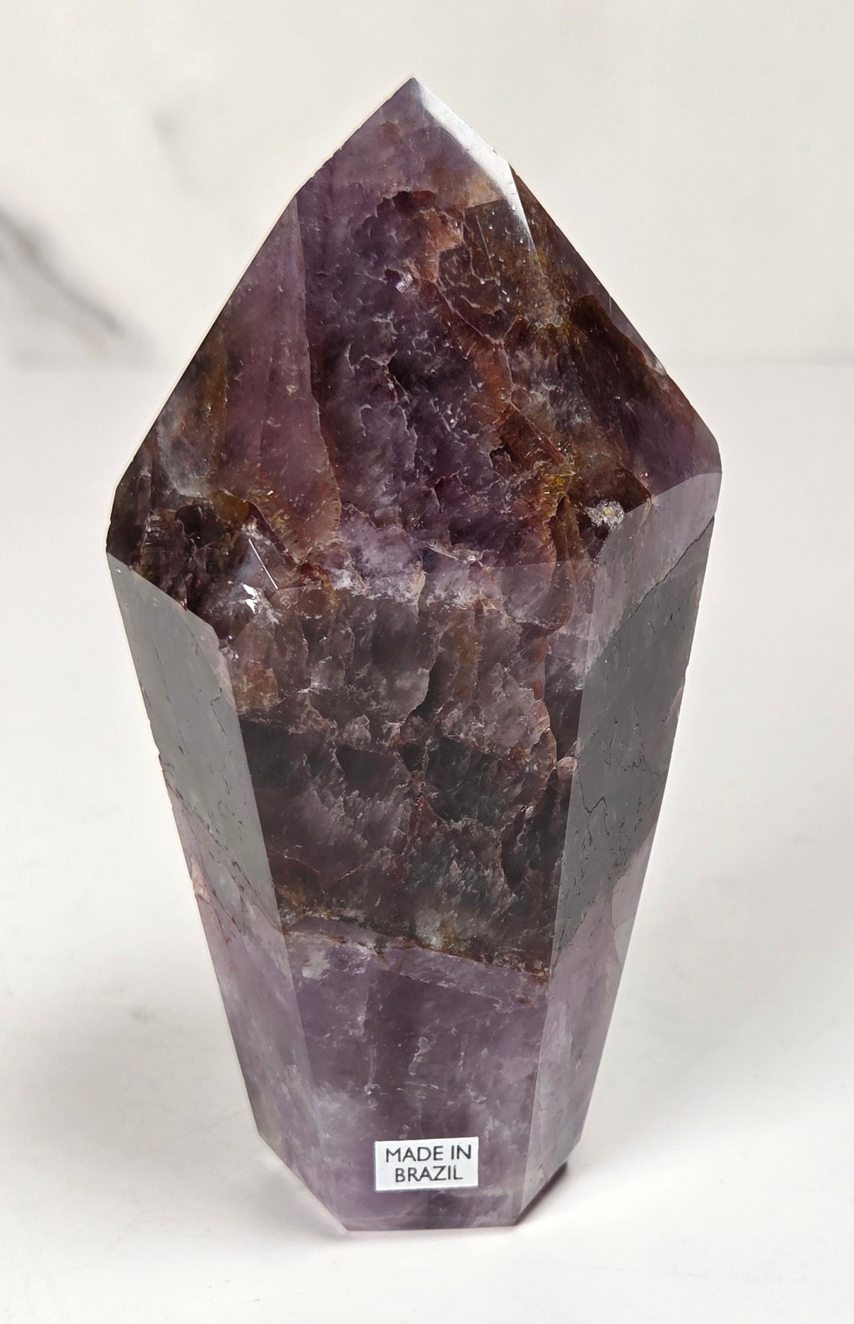 Amethyst crystal carved into a point on a white background