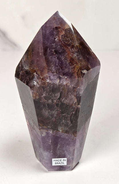 Amethyst crystal carved into a point on a white background