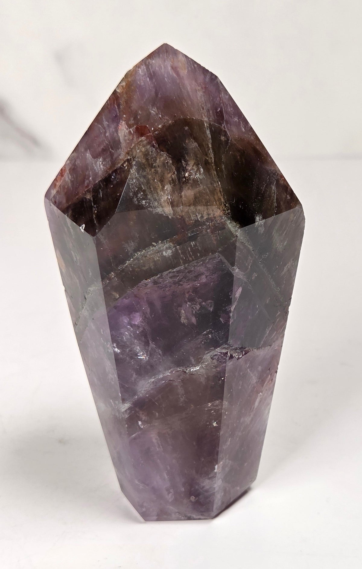 Amethyst crystal carved into a point on a white background