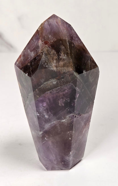 Amethyst crystal carved into a point on a white background