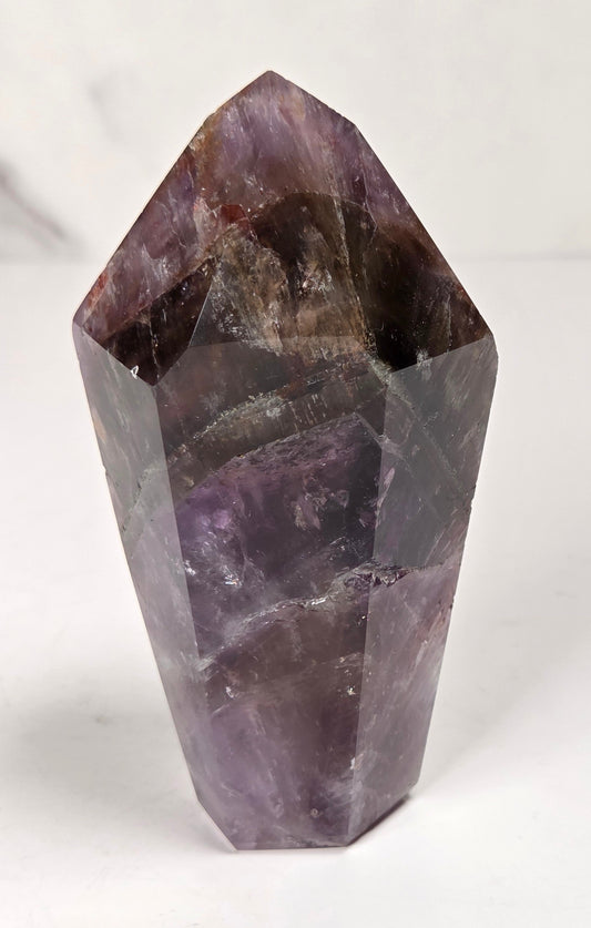 Amethyst crystal carved into a point on a white background