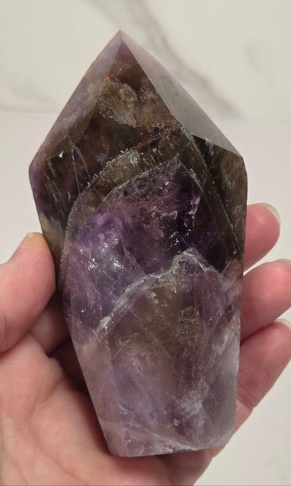 Amethyst crystal carved into a point on a white background