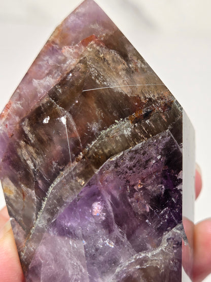 Amethyst crystal carved into a point on a white background