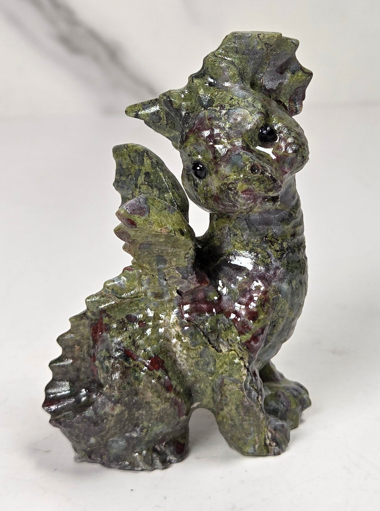 Green and red Dragons Blood dragon carving against a neutral background