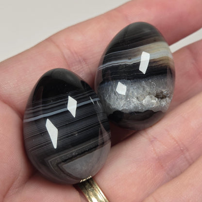 Person holding black and white agate egg shaped stones