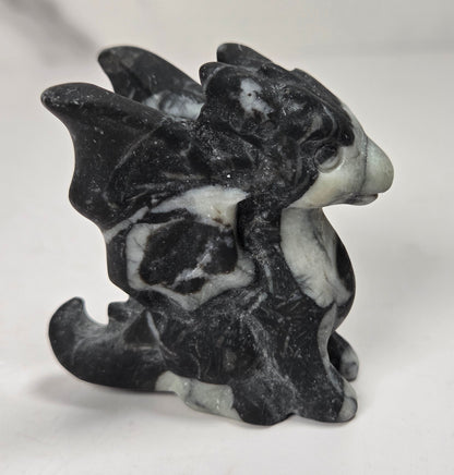 A small carved dragon figurine made from black and white marbled stone, shown from the side on a plain light background.