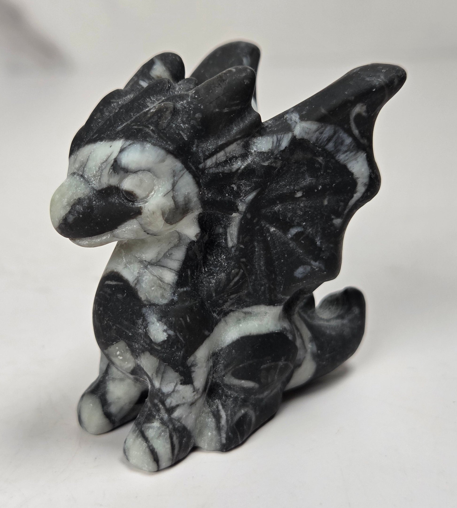 A small dragon figurine carved from black and white marbled stone, shown on a plain light background.