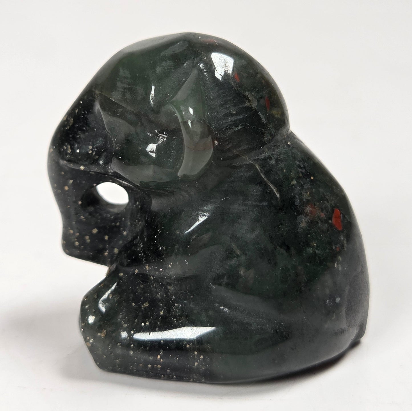 A small polished dark green stone figurine of a seated elephant shown on a plain light background.