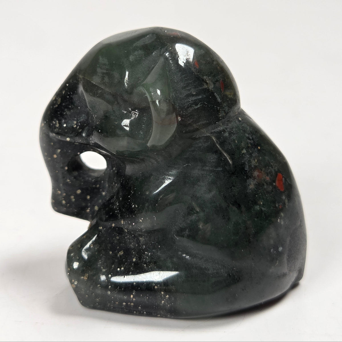 A small polished dark green stone figurine of a seated elephant shown on a plain light background.