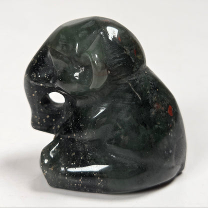 A small polished dark green stone figurine of a seated elephant shown on a plain light background.