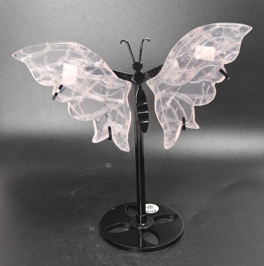 A butterfly-shaped decorative sculpture or wall art piece with translucent pale pink wings and a black stand, photographed against a dark gray studio backdrop.