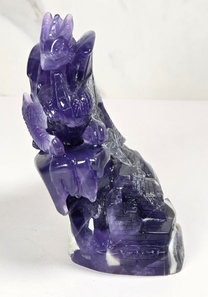 Intricately carved fluorite dragon with purple and white coloring against a marbled background