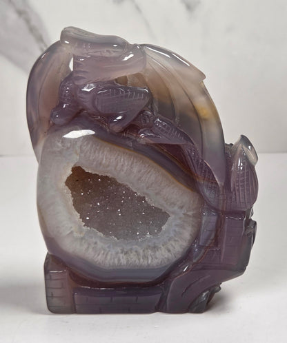 druzy agate carved dragon with a crystal pocket against a marbled background