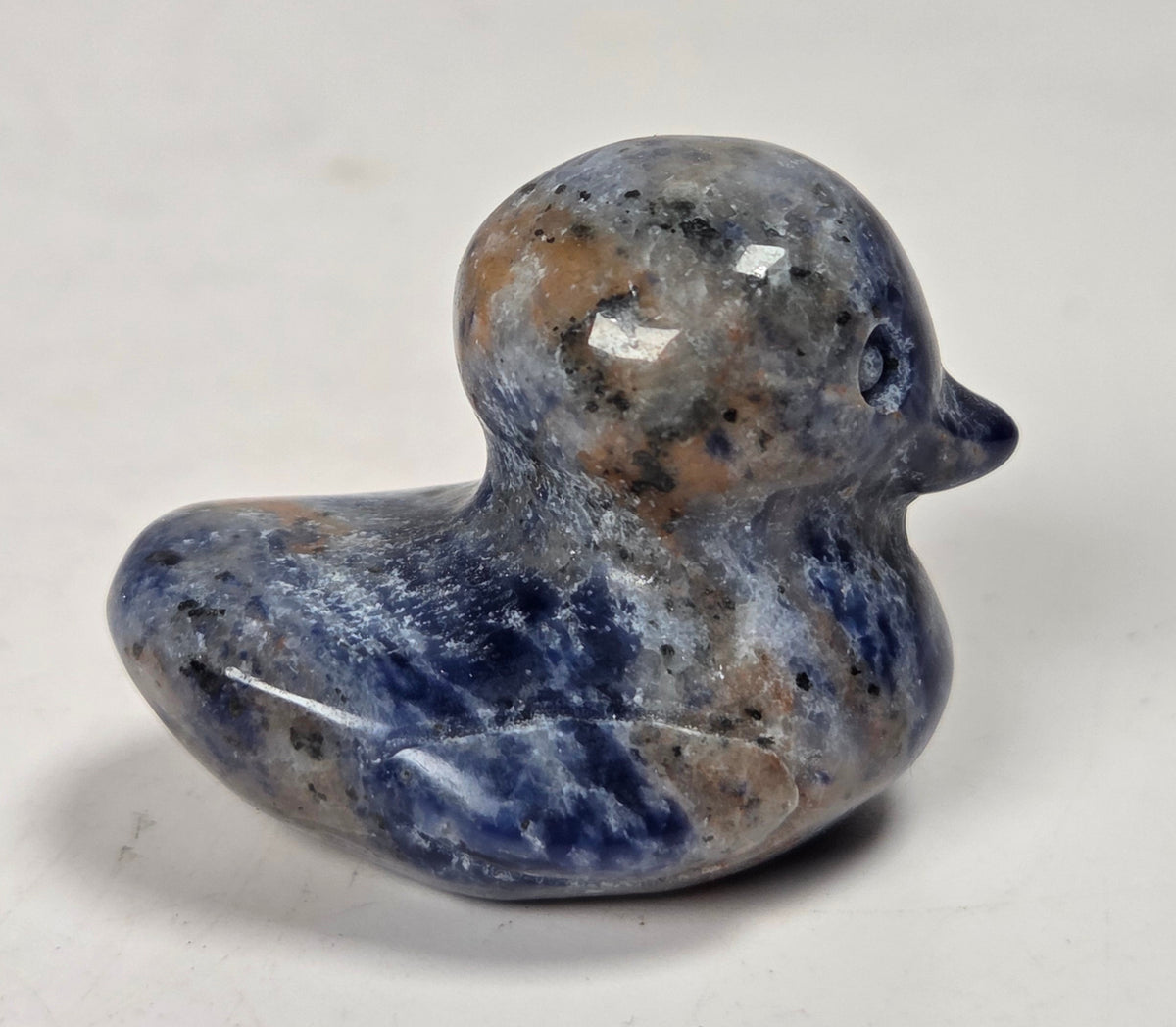 Blue sodalite carving of a duck against a white background