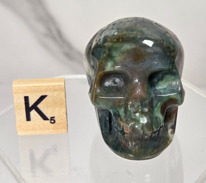 Moss Agate skull carving on a white background
