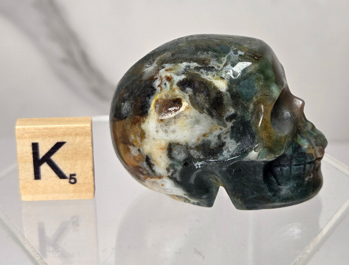 Moss Agate skull carving on a white background
