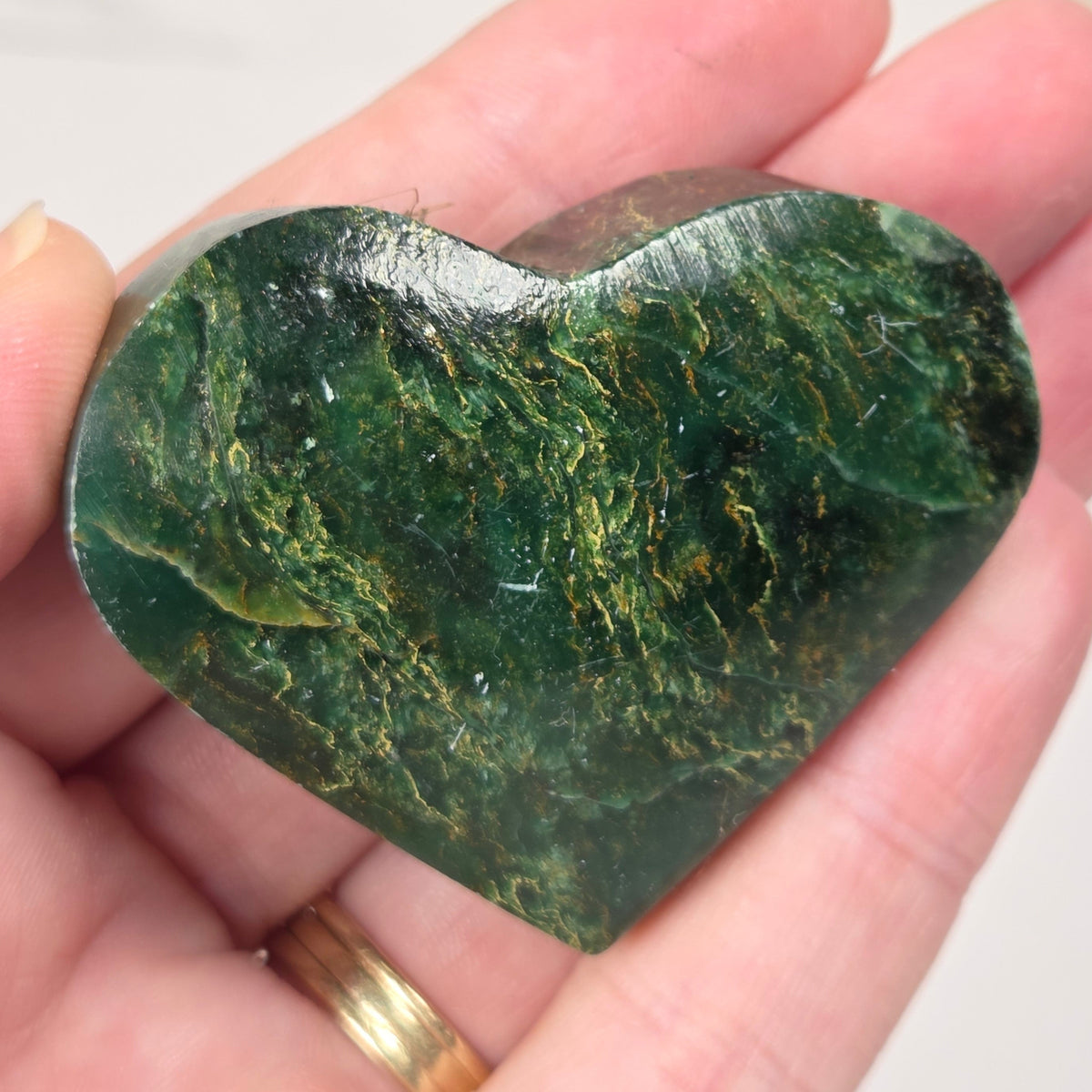 Heart-shaped green stone being held in a hand
