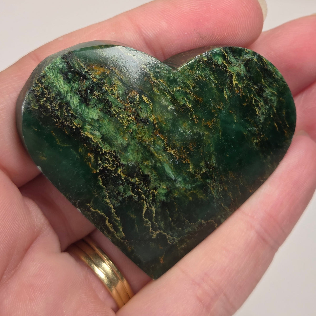 Heart-shaped green stone being held in a hand