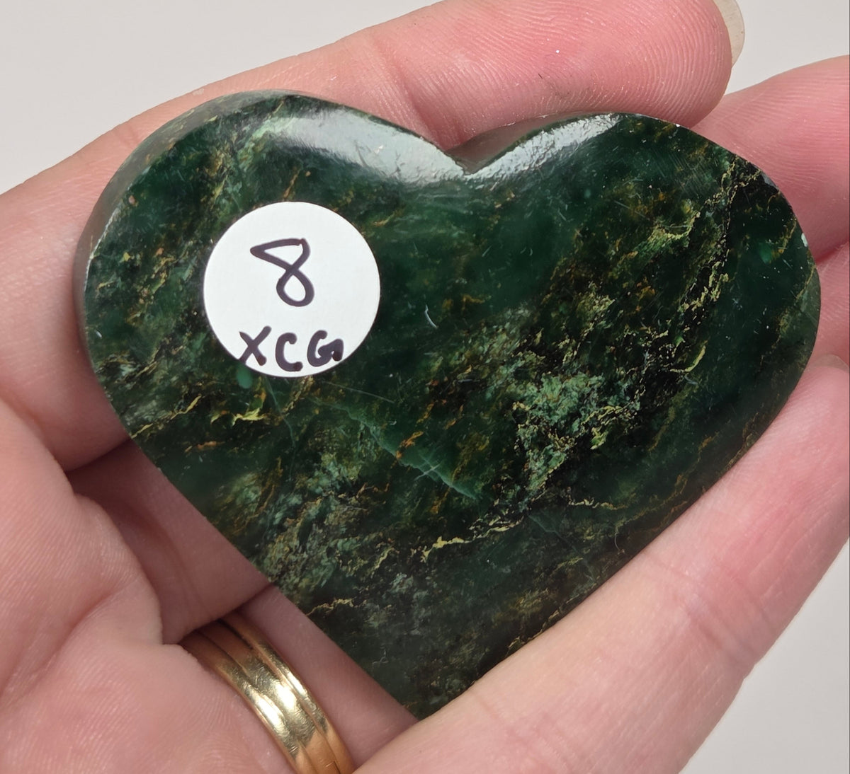 Heart-shaped green stone being held in a hand