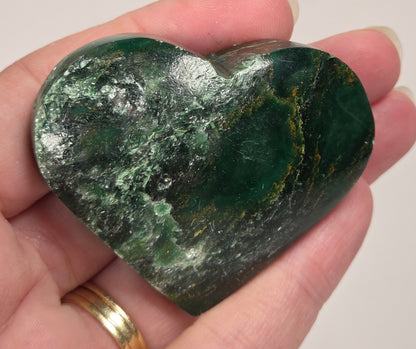 Heart-shaped green stone being held in a hand