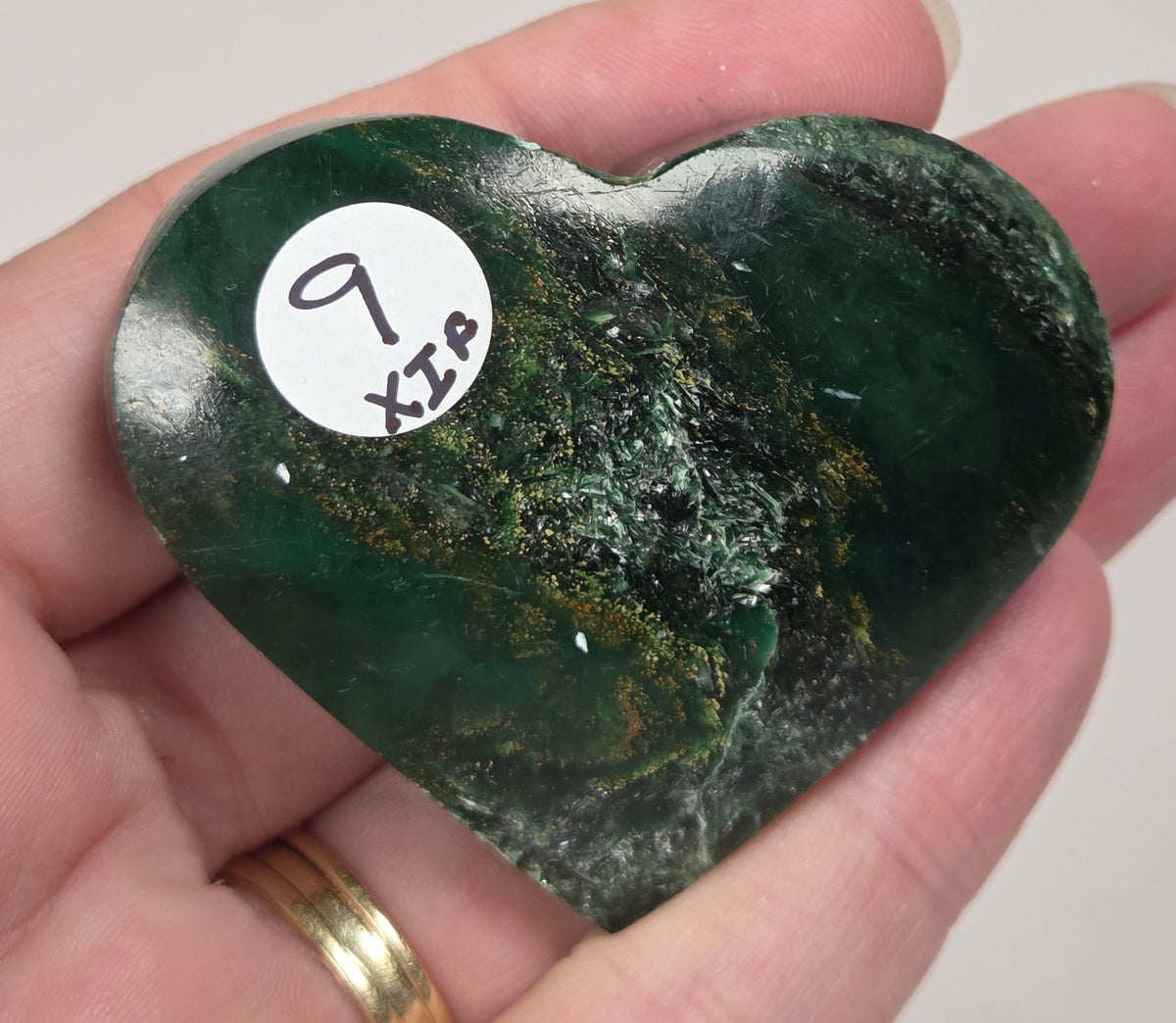 Heart-shaped green stone being held in a hand