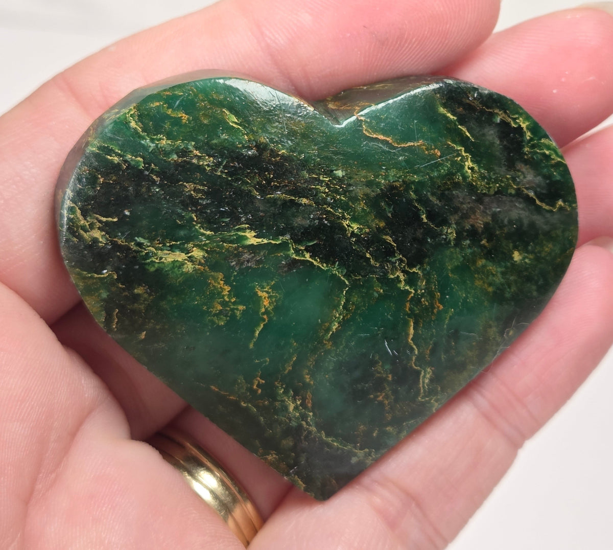 Heart-shaped green stone being held in a hand
