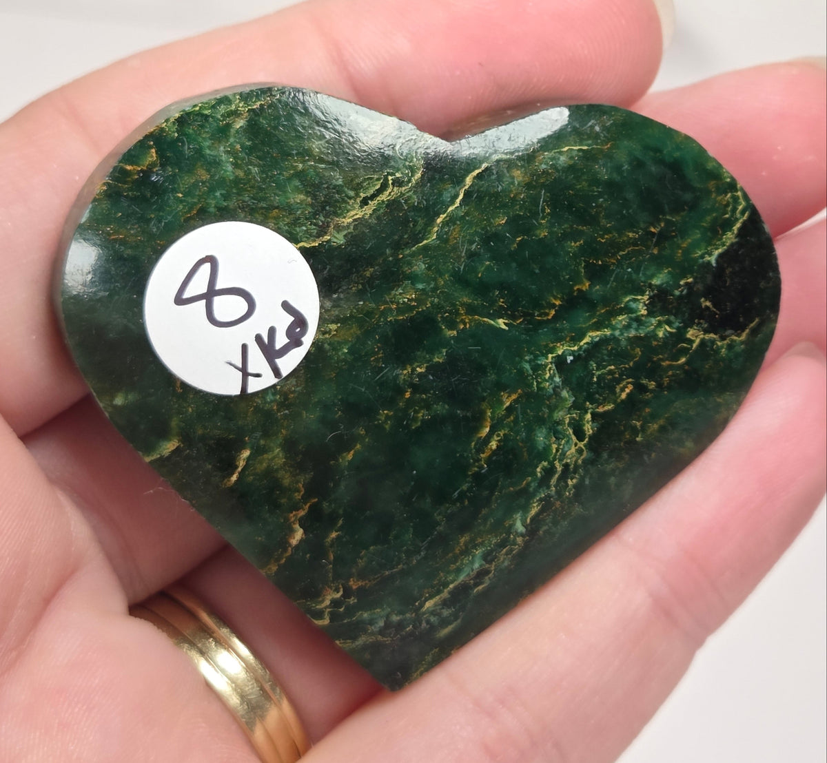 Heart-shaped green stone being held in a hand