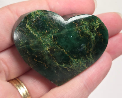 Heart-shaped green stone being held in a hand