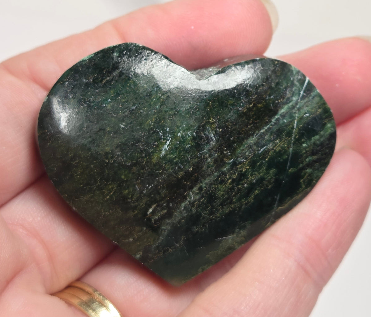 Heart-shaped green stone being held in a hand