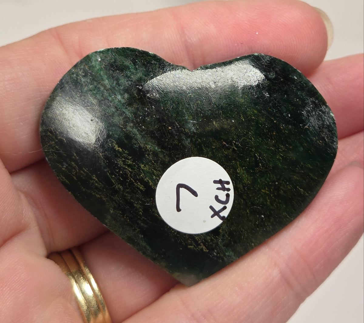 Heart-shaped green stone being held in a hand