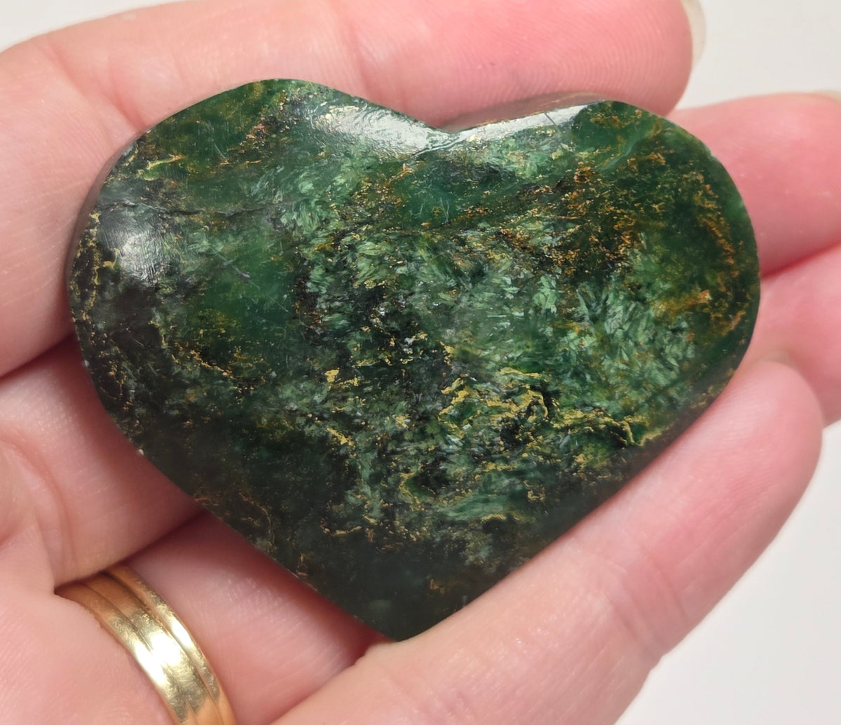 Heart-shaped green stone being held in a hand