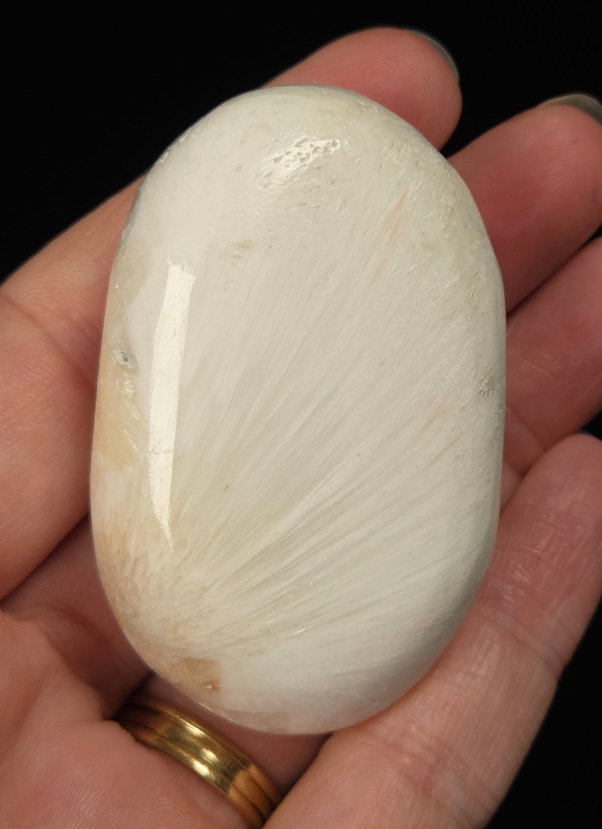 white crystal palm carving being held in a hand against a black background