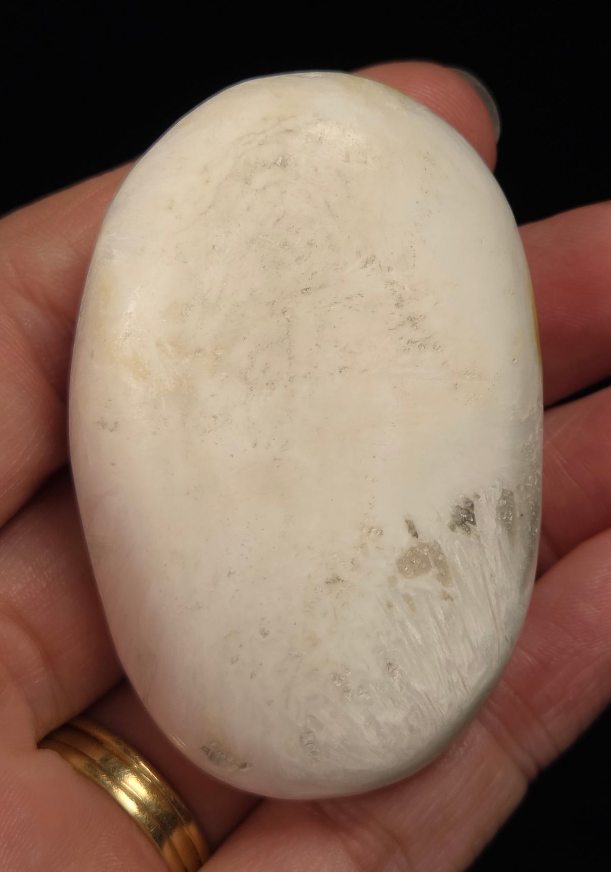 white crystal palm carving being held in a hand against a black background