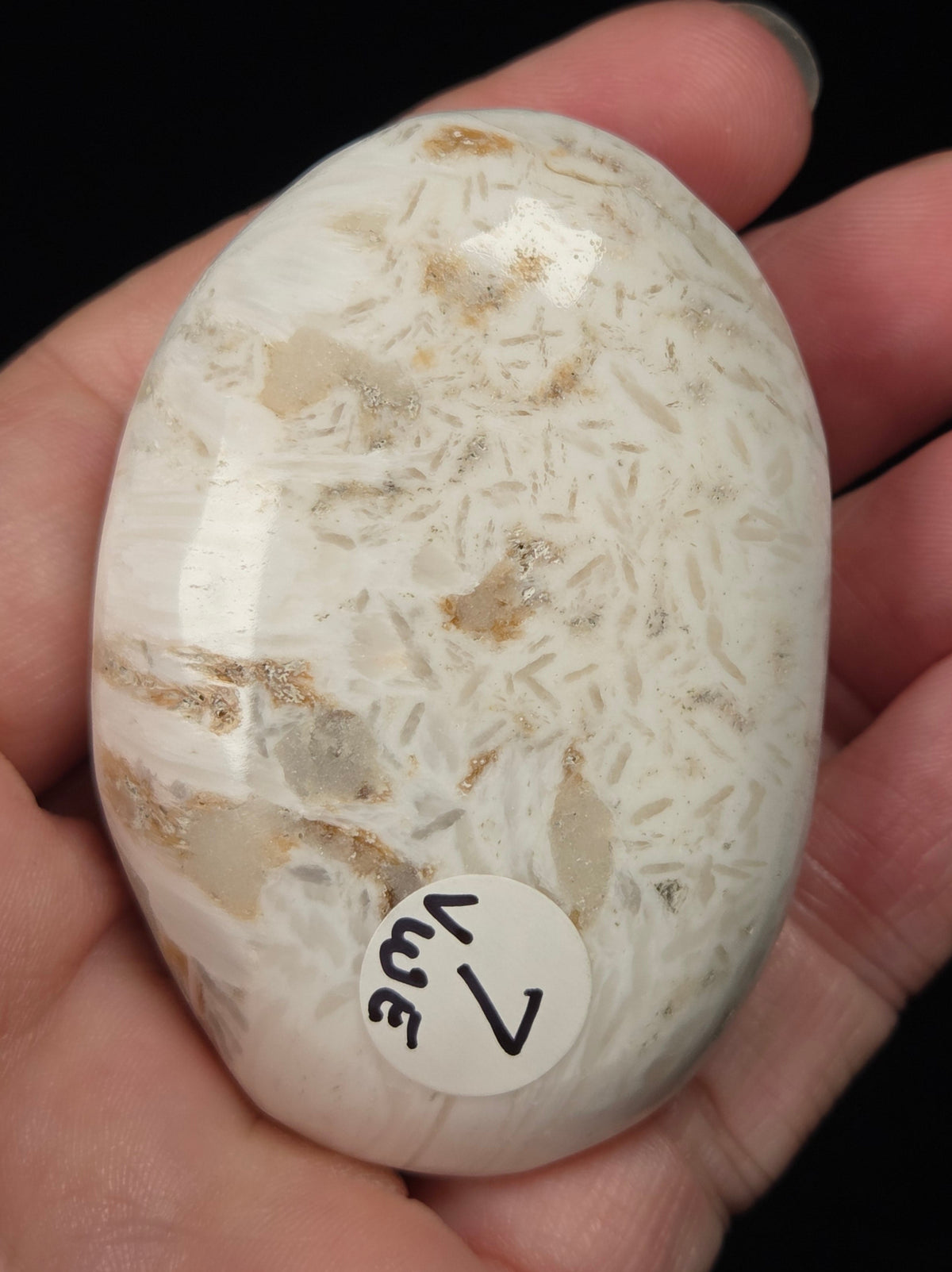 white crystal palm carving being held in a hand against a black background
